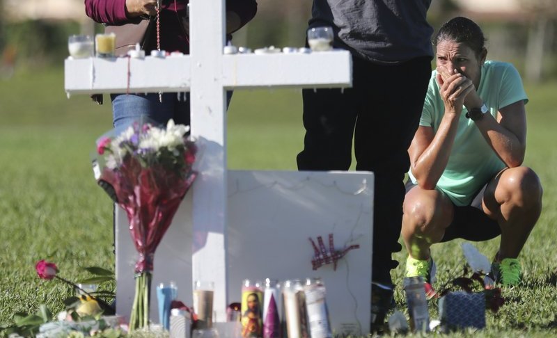 Maria Creed is overwhelmed with emotion as she crouches in front of one of the memorial crosses at Pine Trails Park in Parkland, Fla., Friday, Feb. 16, 2018, that were placed for the victims of the Wednesday shooting at Marjory Stoneman Douglas High School. Creed’s son, Michael Creed, is a sophomore at the school. (Amy Beth Bennett/South Florida Sun-Sentinel via AP)