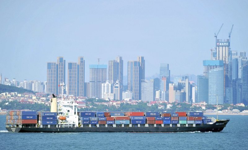 In this Sept. 13, 2018, photo, a container ship sails past the city skyline of Qingdao in eastern China’s Shandong province. (Chinatopix via AP)