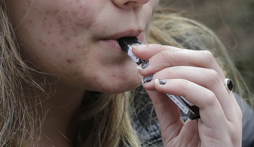 A high school student uses a vaping device near a school campus in Cambridge, Mass. on April 11, 2018. Photo via AP/ Steven Senne.