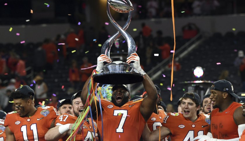 Clemson defensive end Austin Bryant (7) holds up the trophy as the team celebrates their 30-3 win against Notre Dame in the NCAA Cotton Bowl semi-final playoff football game, Saturday, Dec. 29, 2018, in Arlington, Texas. Clemson won 30-3. Photo via AP Photo/Jeffrey McWhorter.