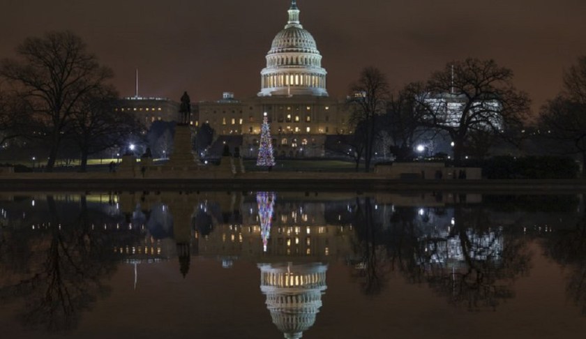 The Capitol is mirrored in the Reflecting Pool in Washington, as a partial government shutdown heads into a second week, Friday night, Dec. 28, 2018. Both chambers of Congress are gone, likely leaving the impasse till next week when the Democrats take control of the House of Representatives. Photo via AP/J. Scott Applewhite.