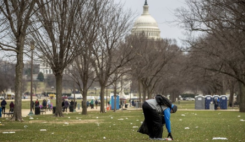The Capitol building is visible as a man who declined to give his name picks up garbage during a partial government shutdown on the National Mall in Washington, Tuesday, Dec. 25, 2018. Photo via AP/Andrew Harnik.