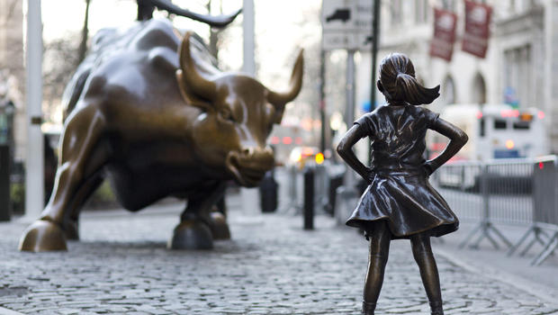 The fearless girl stands before the iconic Wall Street "Charging Bull."