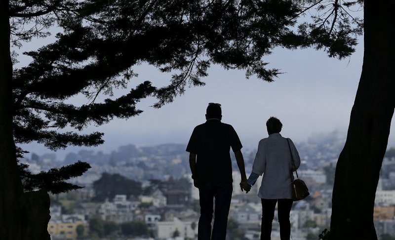 FILE- In this July 3, 2017, file photo a man and woman walk under trees down a path at Alta Plaza Park in San Francisco. Looking at the income, living expenses and life spans of today’s retirees can help you make the right financial moves so your golden years aren’t tarnished by an unexpected shortfall. (AP Photo/Jeff Chiu, File)