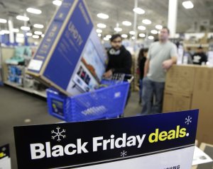 FILE- In this Nov. 22, 2018, file photo people wait in line to buy televisions as they shop during an early Black Friday sale at a Best Buy store on Thanksgiving Day in Overland Park, Kan. The holiday season was a brutal one for U.S. retailers, especially department stores and companies that sell luxury products. (AP Photo/Charlie Riedel, File)