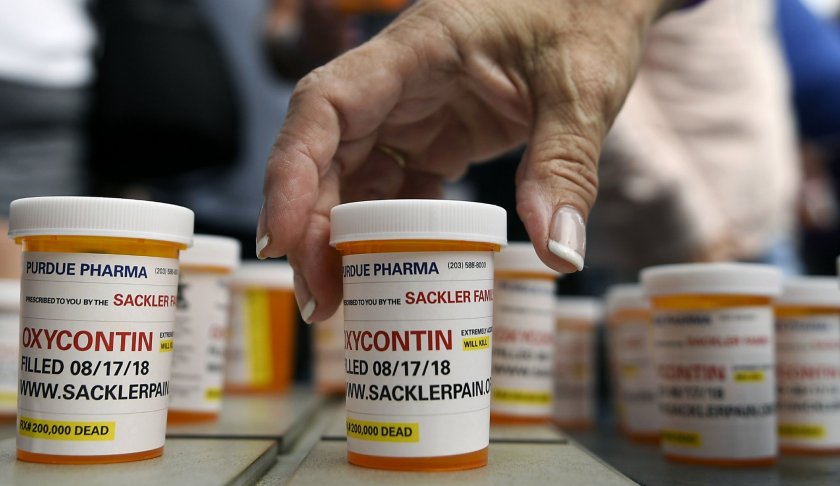 FILE - In this Aug. 17, 2018, file photo, family and friends who have lost loved ones to OxyContin and opioid overdoses leave pill bottles in protest outside the headquarters of Purdue Pharma, which is owned by the Sackler family, in Stamford, Conn. A new filing in a Massachusetts case ramps up the legal and financial pressure against the Sackler family, which owns the company that makes OxyContin. Photo via AP/Jessica Hill, File.