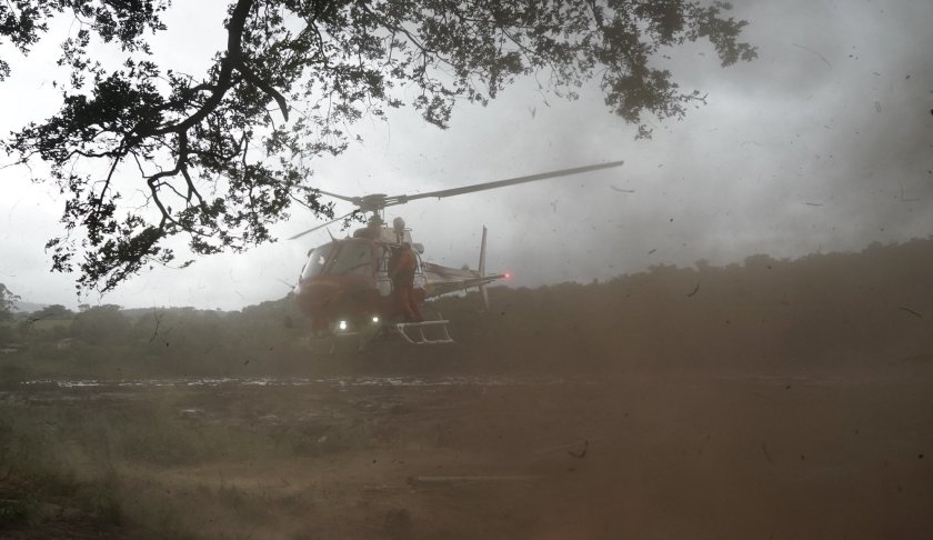 A helicopter takes of carrying a rescued body that was found in the mud, after a dam collapse near Brumadinho, Brazil, Saturday, Jan. 26, 2019. Rescuers in helicopters searched for survivors while firefighters dug through mud in a huge area in southeastern Brazil buried by the collapse of a dam holding back mine waste, with at least nine people dead and up to 300 missing. (AP Photo/Leo Correa)