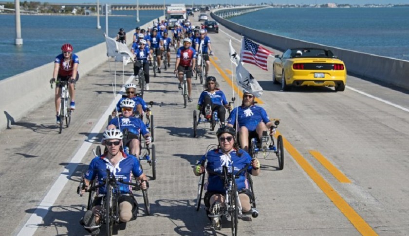 In this photo provided by the Florida Keys News Bureau, injured military personnel including Army Staff Sgt. Sam Oelke, left, retired Air Force Staff Sgt. Jennifer Caudillo, right, and other wounded military personnel ride bicycles on the Seven Mile Bridge during the Florida Keys Soldier Ride Friday, Jan. 11, 2019, near Marathon, Fla. Some 45 men and women are riding bicycles down segments of the Florida Keys Overseas Highway as a facet of an effort organized by the Wounded Warrior Project to raise public awareness and support for the needs of severely injured members of the U.S. military. Photo via AP.