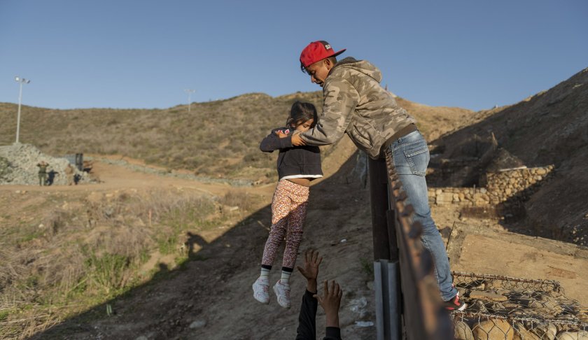 FILE - In this Jan. 3, 2019, file photo, a migrant from Honduras passes a child to her father after he jumped the border fence to get into the U.S. side to San Diego, Calif., from Tijuana, Mexico. The Trump administration says it would require extraordinary effort to reunite what may be thousands of migrant children who have been separated from their parents and, even if it could, the children would likely be emotionally harmed. (AP Photo/Daniel Ochoa de Olza, File)