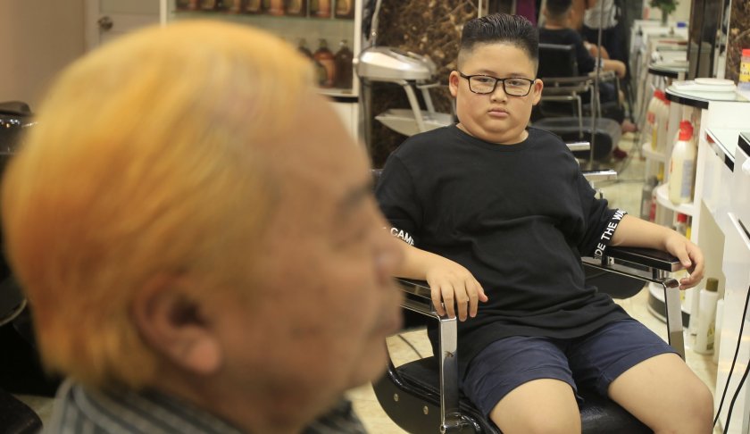 Le Phuc Hai, 66, left, and To Gia Huy, 9, sit after having Trump and Kim haircuts in Hanoi, Vietnam, on Tuesday, Feb.19, 2019. U.S. President Donald Trump and North Korean leader Kim Jong Un have become the latest style icons in Hanoi, a week before their second summit is to be held in the capital city of Vietnam.(AP Photo/Hau Dinh)