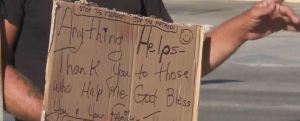 Man panhandles as he holds a sign. (WINK News photo)