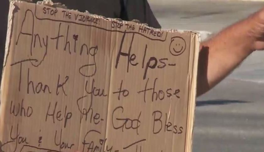 Man panhandles as he holds a sign. (WINK News photo)