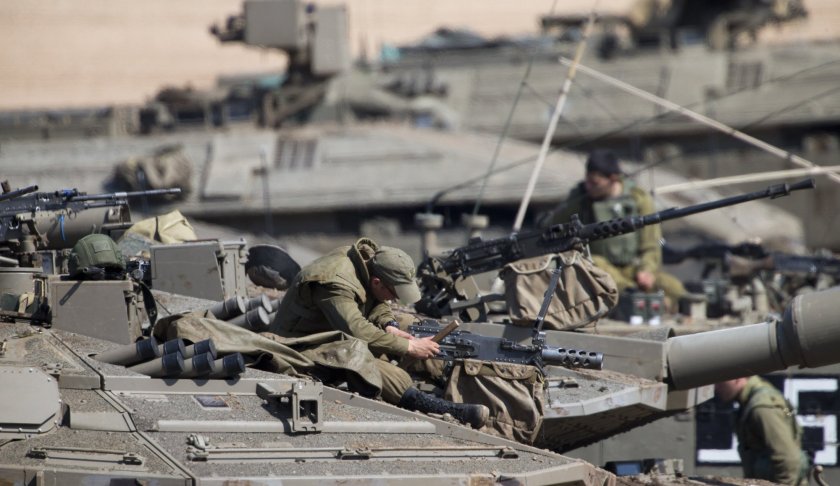 Israeli soldiers work on their tanks at a gathering area near the Israel-Gaza border, Israel, Tuesday, March 26, 2019. Israeli Prime Minister Benjamin Netanyahu returned home from Washington on Tuesday, heading straight into military consultations after a night of heavy fire as Israeli aircraft bombed Gaza targets and the strip's militants fired rockets into Israel. (AP Photo/Ariel Schalit)