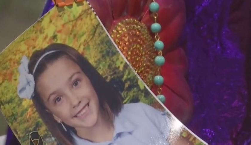 Attendee holds a photo of the 8-year-old girl who died in a hit-and-run crash on March 25. (Credit: WINK News)