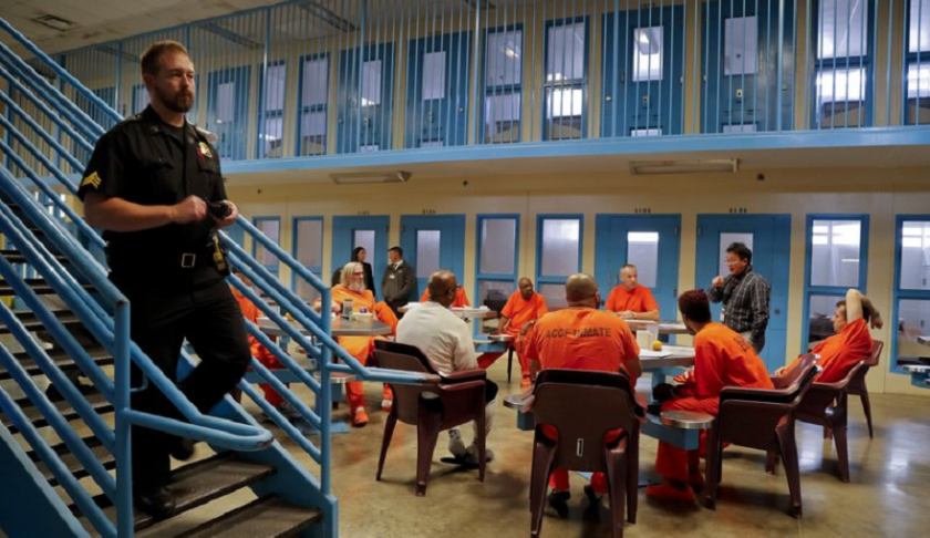 A guard makes his rounds checking cells as inmates gather for a session with Soldier On, Chaplain Quentin Chin inside the veteran's pod at the Albany County Correctional Facility, Monday, Nov. 27, 2017, in Albany, N.Y.(AP Photo/Julie Jacobson)