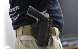 FILE - In this Jan. 5, 2016 file photo, Mike Weinstein, director of training and security at the National Armory gun store and gun range, wears a Ruger 1911 handgun in a holster as he teaches a concealed weapons permit class in Pompano Beach, Fla. Florida might grant authority to 2 million civilians who can lawfully carry guns tucked in waistbands, under jackets or inside purses into restaurants, shopping malls and elsewhere. (AP Photo/Lynne Sladky, File)