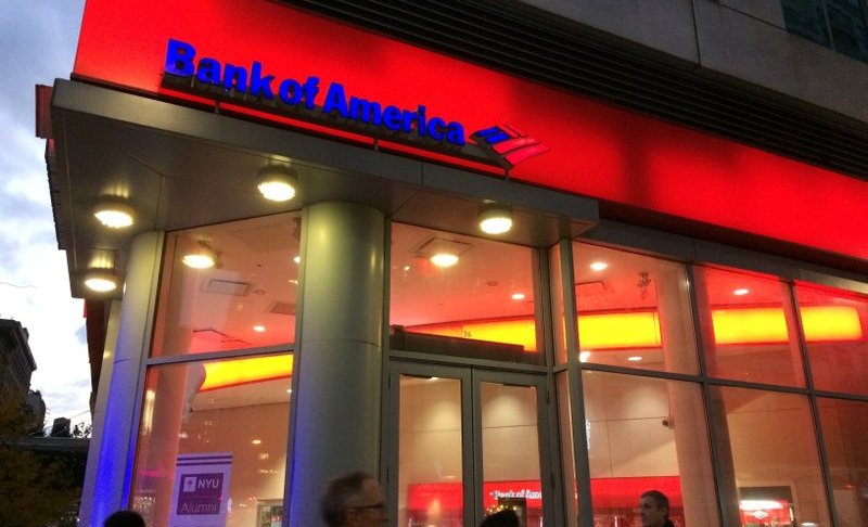 FILE- In this Nov. 6, 2017, file photo, people walk by a branch office of Bank of America in New York. Bank of America is raising its starting pay to $20 an hour over a two-year period, starting with a hike next month. The company said Tuesday, April 9, 2019, that it is raising its minimum hourly wage to $17 on May 1 and will continue to increase the pay until it hits $20 an hour in 2021. (AP Photo/Mark Lennihan, File)