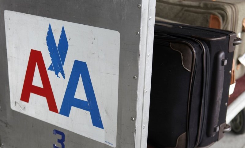 FILE - In this Nov. 29, 2011 file photo, an American Airlines symbol is displayed on the side of a luggage cart at LaGuardia Airport in New York. American Airlines says it's cutting the cost of checking oversized sporting gear and musical instruments on flights. American said Tuesday, May 21, 2019, that it eliminated the extra oversize charge for those items and instead will charge regular bag fees, which are lower. (AP Photo/Seth Wenig, File)
