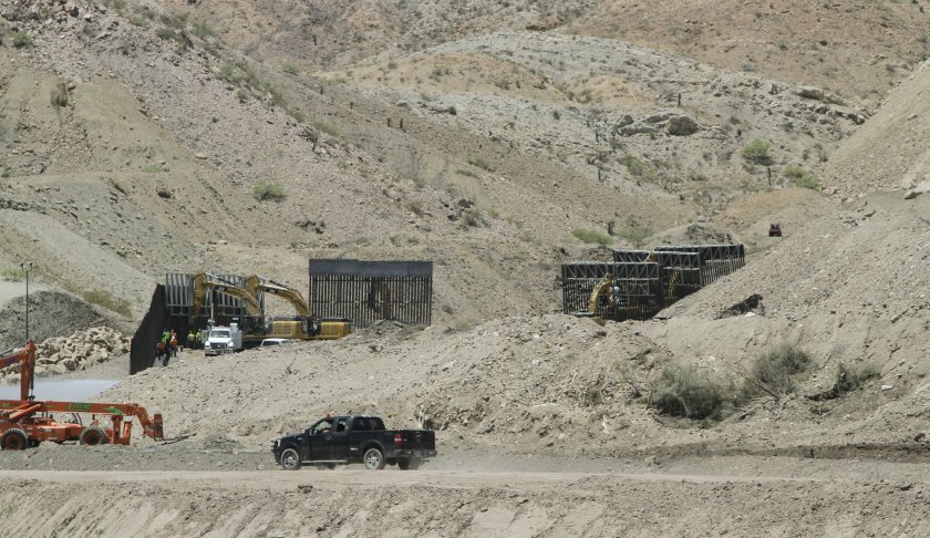 In a May 25, 2019 photo, construction workers install sections of fencing for a privately-funded border fence on private land in Sunland Park, New Mexico. A leader with the group that's been raising funds to build a southern border wall on its own says they erected less than a mile of wall on private land in New Mexico over Memorial Day weekend. (AP Photo/Cedar Attanasio)
