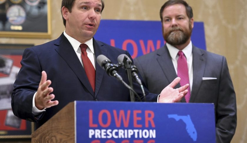 FILE: Florida Gov. Ron DeSantis speaks about the need to lower prescription costs by importing drugs from other countries, Tuesday, June 11, 2019, at the Eisenhower Recreation Center in The Villages, Fla. Listening at right is state Sen. Aaron Bean. (Max Gersh/Daily Sun via AP/FILE)