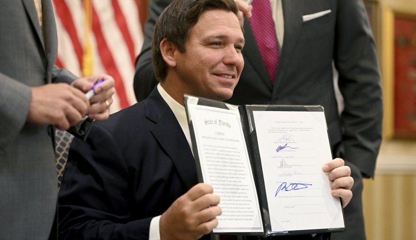 Florida Gov. Ron DeSantis holds up a bill allowing the import of cheaper prescription drugs from other countries after signing it, Tuesday, June 11, 2019, at the Eisenhower Recreation Center in The Villages, Fla. (Max Gersh/Daily Sun via AP)