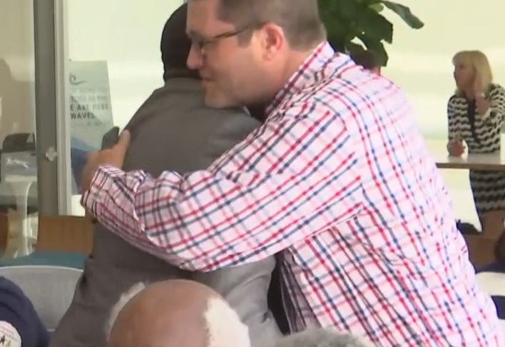 Men hug at the meeting. (Credit: WINK News)