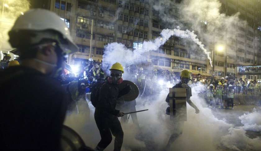 Protesters react to tear gas during a confrontation with riot police in Hong Kong Sunday, July 21, 2019. Hong Kong police launched tear gas at protesters Sunday after a massive pro-democracy march continued late into the evening. The action was the latest confrontation between police and demonstrators who have taken to the streets to protest an extradition bill and call for electoral reforms in the Chinese territory. (Eric Tsang/HK01 via AP)