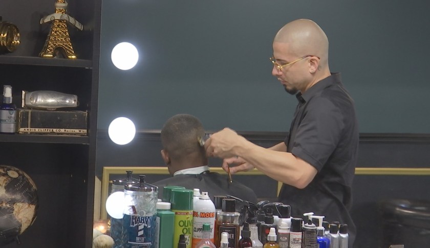Ivan Suarez as he cuts the hair of a patron at his barber shop. (Credit: WINK News)