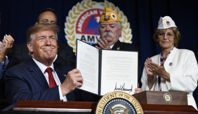 President Donald Trump holds up a presidential memorandum that he signed that discharges the federal student loan debt of totally and permanently disabled veterans following his speech at the American Veterans (AMVETS) 75th National Convention in Louisville, Ky., Wednesday, Aug. 21, 2019. (AP Photo/Susan Walsh)