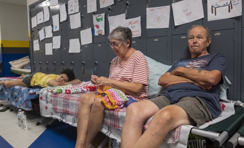 Gordon and Dina Reynolds, with their 11-year-old granddaughter, Abby, sit on cots in the hall way of the North Myrtle Beach High School that is currently being used as a Red Cross evacuation shelter Wednesday, Sept. 4, 2019 in North Myrtle Beach, S.C. Weakened but still deadly, Hurricane Dorian crept up the Southeastern coast of the United States and millions were ordered to evacuate as forecasters said near-record levels of seawater and rain could inundate Georgia and the Carolinas. (Jason Lee/The Sun News via AP)
