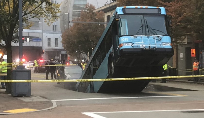 Authorities investigate after a Port Authority bus was caught in a sinkhole in downtown Pittsburgh on Monday, Oct. 28, 2019. The Port Authority of Allegheny County says the lone passenger is being treated Monday morning for minor injuries. (Darrell Sapp/Pittsburgh Post-Gazette via AP)