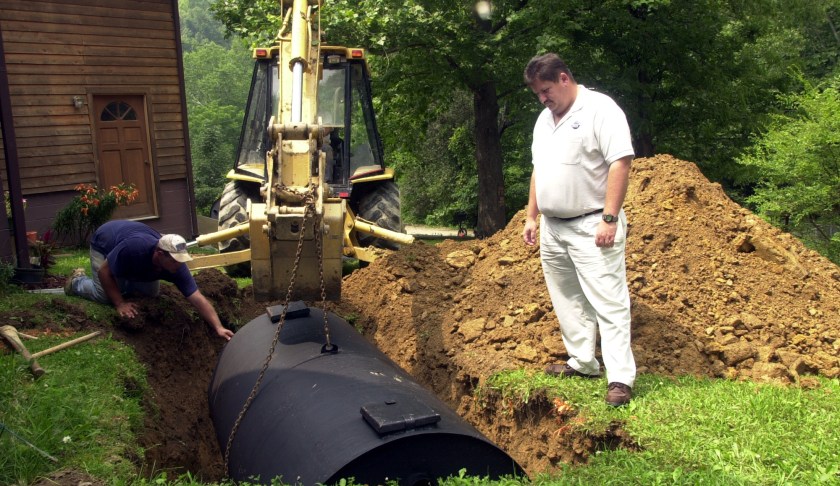 FILE: Tony Lewis, left, PRIDE coordinator in Perry County, watches as Paul Lewis maneuvers a septic tank into place Monday, July 15, 2002, in Happy, Ky. (AP Photo/Rhonda Simpson/FILE)
