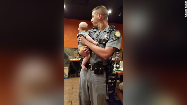 Kentucky State Trooper Aaron Hampton held a fussing baby so his mother could finish her meal. (Credit: CNN)