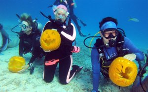 In this Saturday, Oct. 5, 2019, photo provided by the Florida Keys News Bureau, scuba divers display their creations during the Underwater Pumpkin Carving Contest in the Florida Keys National Marine Sanctuary off Key Largo, Fla. Some two dozen divers participated in the competition, coordinated by the Amoray Dive Resort, 30 feet beneath the surface of the Atlantic Ocean. (Frazier Nivens/Florida Keys News Bureau via AP)
