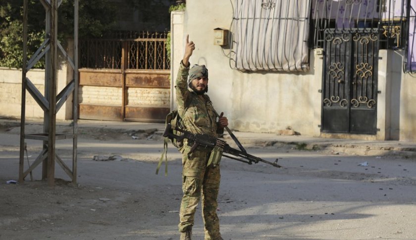 In this Saturday, Oct. 12, 2019 photo, Turkey-backed Syrian fighter stand in Ras al-Yan, Syria.Turkey's military says it has captured a key Syrian border town Ras al-Ayn under heavy bombardment in its most significant gain as its offensive against Kurdish fighters presses into its fourth day. (AP Photo)