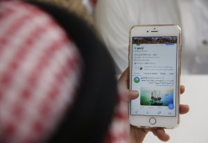 A man reads Aramco's twitter page at a coffee shop in Jiddah, Saudi Arabia, Sunday, Nov. 3, 2019. Saudi Arabia formally started its long-anticipated initial public offering of its state-run oil giant Saudi Aramco on Sunday, which will see a sliver of the firm offered on a local stock exchange in hopes of raising billions of dollars for the kingdom. (AP Photo/Amr Nabil)