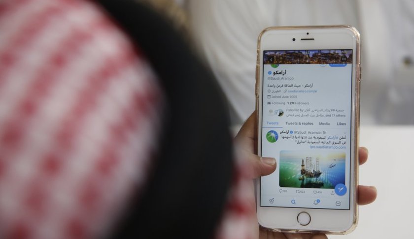 A man reads Aramco's twitter page at a coffee shop in Jiddah, Saudi Arabia, Sunday, Nov. 3, 2019. Saudi Arabia formally started its long-anticipated initial public offering of its state-run oil giant Saudi Aramco on Sunday, which will see a sliver of the firm offered on a local stock exchange in hopes of raising billions of dollars for the kingdom. (AP Photo/Amr Nabil)