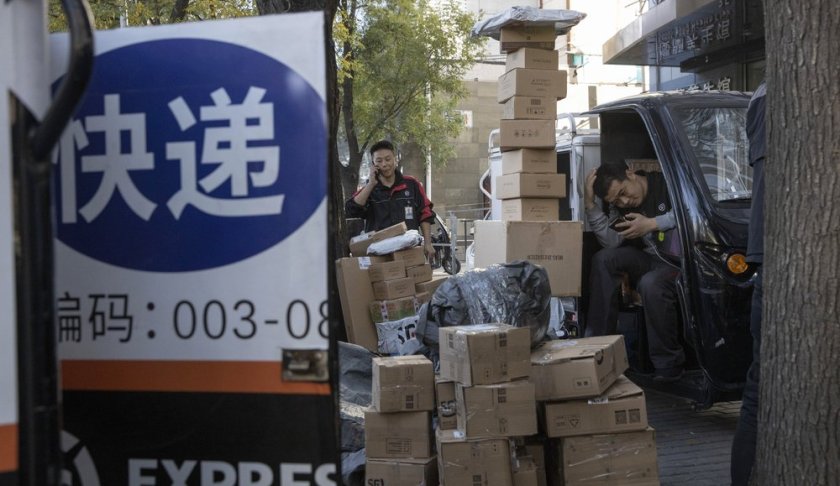 Delivery men wait to distribute parcels on the streets of Beijing on Monday, Nov. 11, 2019. Chinese e-commerce giants Alibaba and JD.com reported a total of more than $50 billion in sales on Monday in the first half of Singles Day, an annual marketing event that is the world's busiest online shopping day. The sign reads "Delivery." (AP Photo/Ng Han Guan)