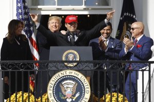 President Donald Trump stands with Washington Nationals catcher Kurt Suzuki, during an event to honor the 2019 World Series champion Washington Nationals on the balcony of the White House, Monday, Nov. 4, 2019, in Washington, as First Lady Melania Trump, left, and Washington Nationals coach Dave Martinez, second from right and general manager Mike Rizzo, far right, look on. Suzuki is wearing a Make America Great Again hat. (AP Photo/Patrick Semansky)