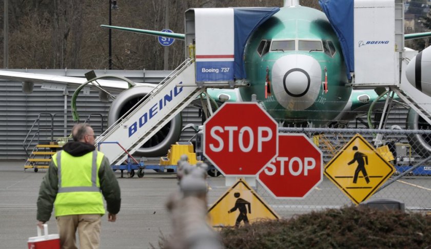 A Boeing worker walks in view of a 737 MAX jet Monday, Dec. 16, 2019, in Renton, Wash. Shares of Boeing fell before the opening bell on a report that the company may cut production of its troubled 737 MAX or even end production all together. (AP Photo/Elaine Thompson)