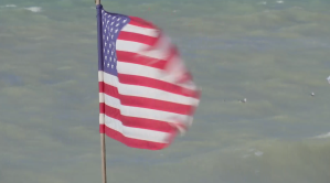 Rip currents at Englewood Beach seen behind an American flag. (Credit: WINK News)