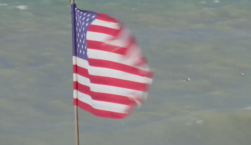 Rip currents at Englewood Beach seen behind an American flag. (Credit: WINK News)