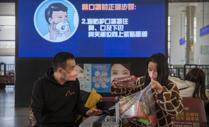 FILE: Travelers wear face masks as a screen shows a video about the proper way to wear a mask at the Beijing Railway Station in Beijing, Friday, Jan. 31, 2020. (AP Photo/Mark Schiefelbein/FILE)