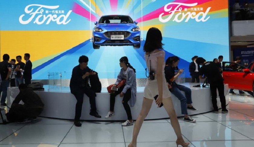 FILE - In this April 25, 2018, file photo, attendees visit the Ford booth during Auto China 2018 show held in Beijing, China. China’s government says it will postpone planned punitive tariffs on U.S.-made automobiles and other goods following an interim trade deal with Washington. Sunday, Dec. 15, 2019’s announcement came after Washington agreed to postpone a planned tariff hike on $160 billion of Chinese goods and to cut in half penalties that already were imposed. (AP Photo/Ng Han Guan, File)