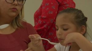 Little girl eats food made from a Crock Pot at an event in Immokalee on Tuesday teaching families healthy cooking techniques. (Credit: WINK News)