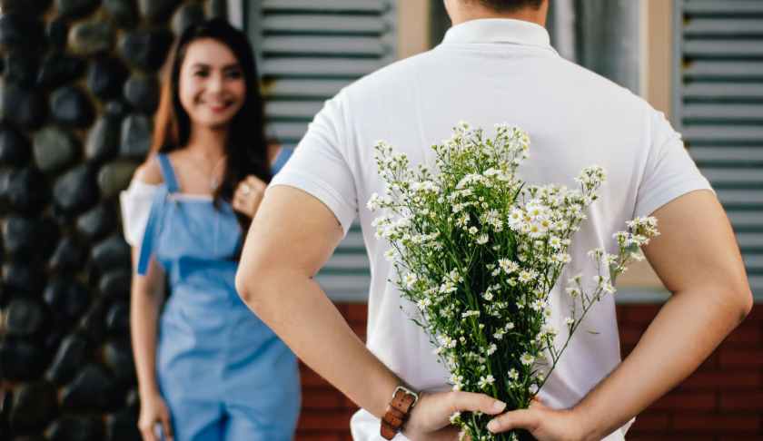 man holding baby s breath flower in front of woman standing near marble wall