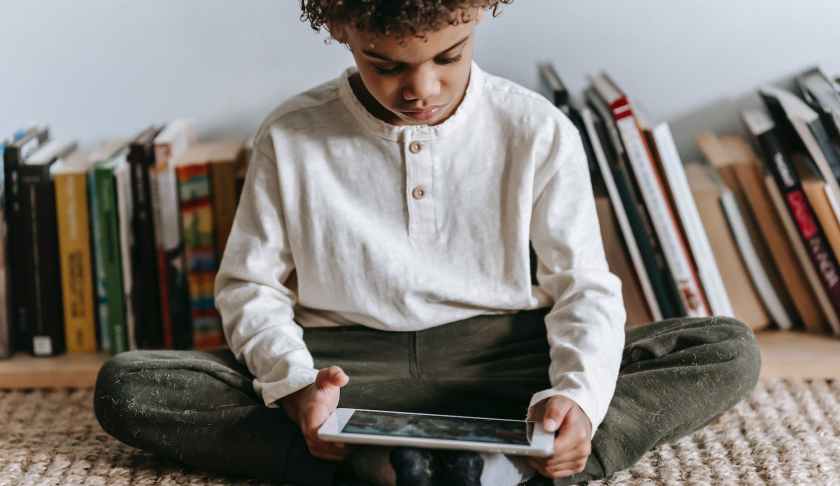 crop black boy browsing tablet in room