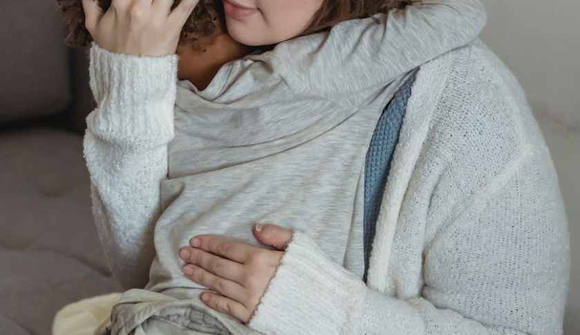 loving mother comforting crying son on couch