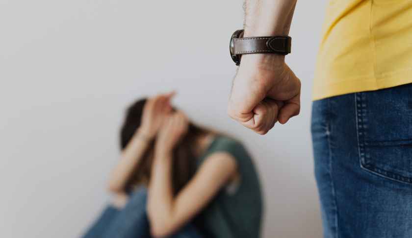 man clenching fist near a woman covering face while sitting