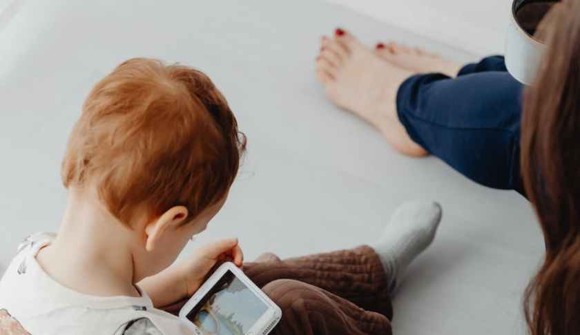 photo of a boy sitting while watching on a mobile phone